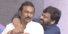 two men are hugging each other and laughing while sitting next to each other on a couch .