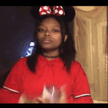 a girl wearing minnie mouse ears and a red hoodie