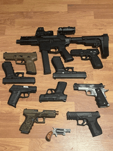 a bunch of guns are lined up on a wooden surface