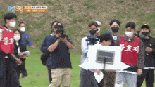 a group of people wearing masks are standing in a field and one of them is wearing a red vest with chinese writing