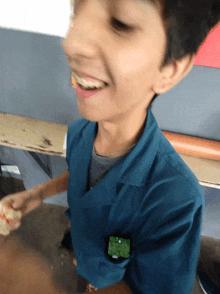 a young boy wearing a blue shirt with a green badge on his pocket