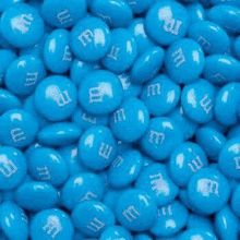 a pile of blue m & m 's candies with white letters on them .