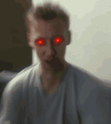 a blurry picture of a man with red eyes and a gray shirt .