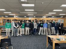 a group of young men are posing for a picture in a library with a man in a suit .