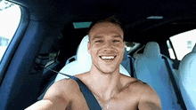 a shirtless man is sitting in the back seat of a car .