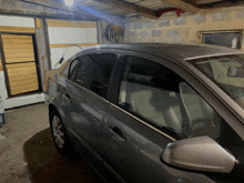 a gray car is parked in a garage with a door open