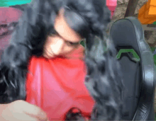 a man with long black hair is wearing a red shirt