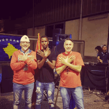 three men standing in front of a flag with the word kosovo