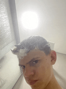 a young man is taking a selfie with his hair covered in foam