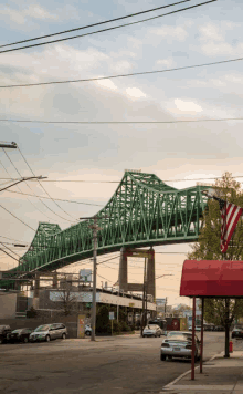 a green bridge over a city street with a red awning