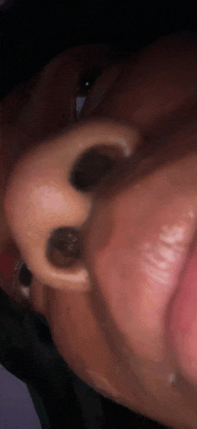 a close up of a person 's nose with their tongue out .