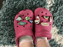 a person wearing a pair of pink crocs with a lot of charms on them