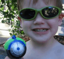 a young boy wearing green sunglasses is holding a toy motorcycle