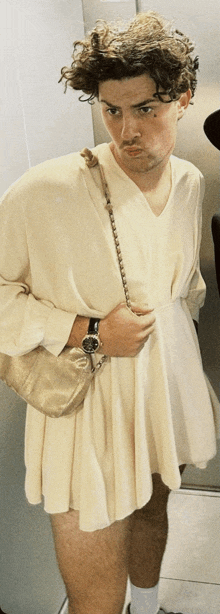 a man in a white dress with a gold purse