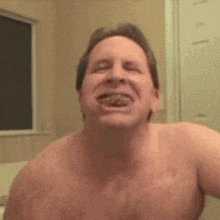 a shirtless man is taking a bath and making a funny face in the bathroom .