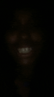 a close up of a person 's face in the dark with a smile on it .