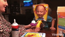 a little girl is playing a game with whipped cream on her face and a can of lucerne whipped cream in front of her