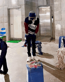 a man wearing a sweater that says " mud " is standing in a room