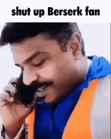 a man with a mustache is talking on a cell phone with the words `` shut up berserk fan '' above him .