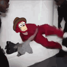 a cartoon of a monkey wearing a hat and red pants laying on the floor