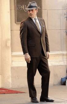 a man in a suit stands in front of a sign that says hotel alysian