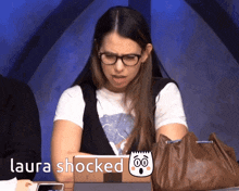 a woman sitting in front of a laptop with the words laura shocked written on the screen