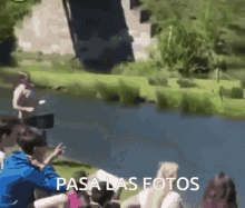 a group of people are standing in front of a body of water with the words pasa las fotos in the corner