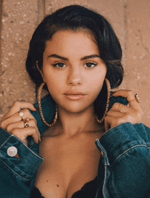 a close up of a woman wearing a denim jacket and hoop earrings