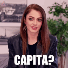 a woman in a leather jacket is making a funny face and saying capita .