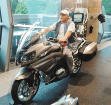 a man is riding a motorcycle in front of a tour sign