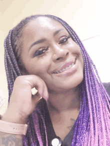 a woman with purple braids and braces smiles