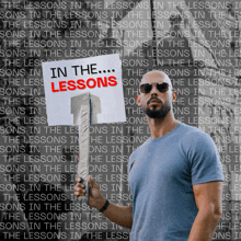 a man holding a sign that says " in the lessons "