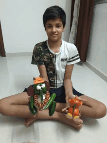 a boy sitting on the floor holding a toy made out of vegetables