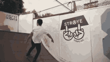 a skateboarder is doing a trick in front of a sign that says straye xxx