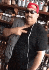 a man wearing a red hat and sunglasses is standing in front of a shelf of liquor .