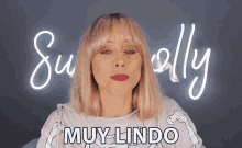 a woman with pink hair stands in front of a neon sign that says muy lindo