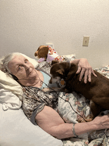 an elderly woman laying in a bed with a dog