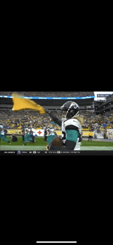 a football player is waving a yellow flag on a field during a game .