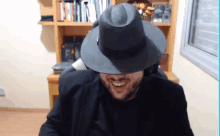 a man wearing a hat and a black jacket is smiling .