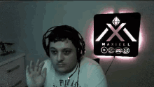 a man wearing headphones with the maxell logo behind him