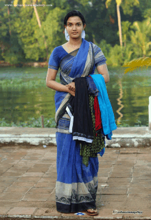 a woman in a blue saree stands in front of a lake