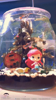 a glass jar filled with fish and a little mermaid figurine