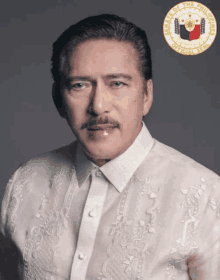 a man is wearing a white shirt with the seal of the state of the philippines behind him