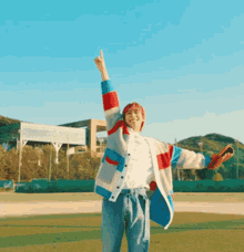 a young man is standing on a baseball field with his arms in the air and giving a thumbs up .