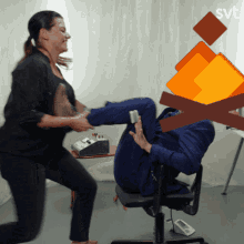 a woman is kicking a man in a chair with a svt logo behind her