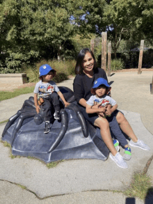 a woman sits on a giant spider with two young boys sitting on it