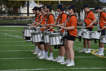 a marching band is playing their drums on a football field