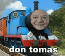 a thomas the tank engine with a man 's face on it is on the tracks .