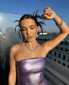 a woman wearing a purple strapless top and a silver chain necklace