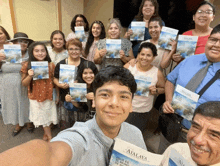 a group of people are posing for a selfie while holding a copy of the atalaya